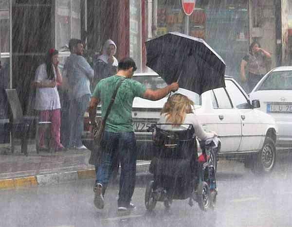 14. Yağmurda kendisi ıslanma pahasına engelli kadınla şemsiyesini paylaşan Bursalı genç.