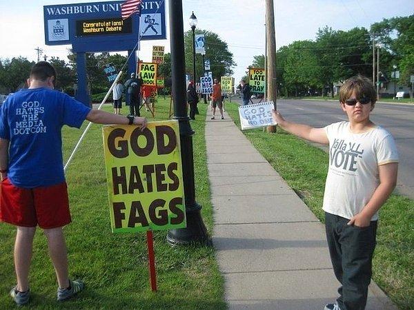 15. Eşcinselliğe karşı eylem yapan "Tanrı Eşcinsellerden Nefret Ediyor" pankartı taşıyan birinin yanında "Tanrı Kimseden Nefret Etmez" yazısı açan cesur genç.