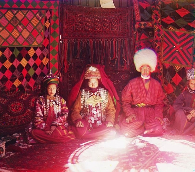 2. Dört kişi duvar halıları önünde oturuyorlar.