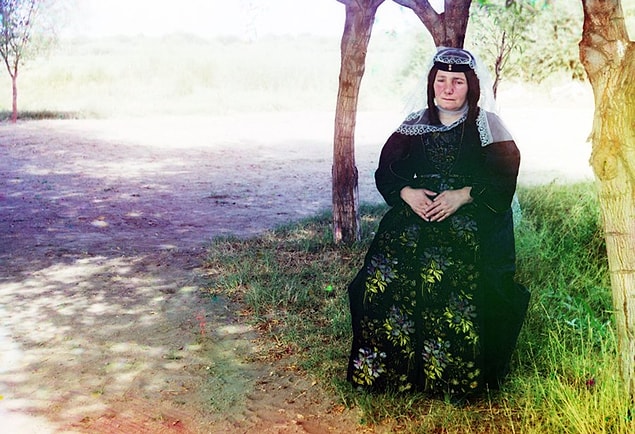 12. Geleneksel bir elbise giyen kadın fotoğraf çektirmek için poz vermiş.