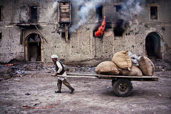 7. ‘Yanan bir evin önünden taşıdığı araba ile geçen bir Hazara’, 1985.