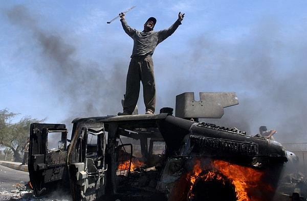 11. Bağdat'ta yanan bir Humvee üstündeki Iraklı..