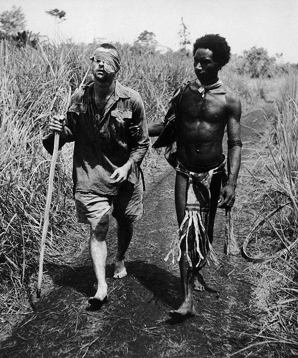 1. 2. Dünya Savaşı sırasında bir Papua Yeni Gine yerlisi, yaralanmış Avustralya askerine çalılıklardan çıkabilmesi için yardımcı oluyor.