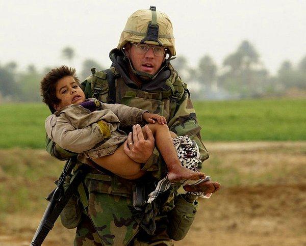 4. Irak savaşı sırasında asker, yaralı küçük çocuğu çatışma alanından uzaklaştırmaya çalışıyor.