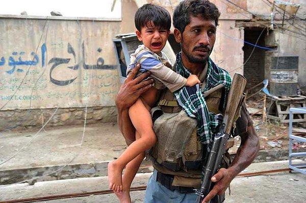 6. Afgan askeri ağlayan çocuğu patlamanın olduğu bölgeden uzaklaştırmaya çalışıyor.