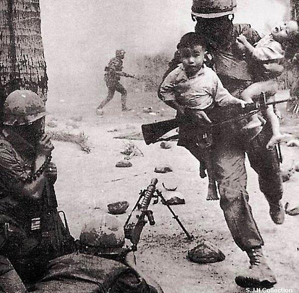13. Vietnam'da bir asker, ateş hattındaki iki çocuğu kucağına alarak bölgeden uzaklaştırmaya çalışıyor. (Vietnam Savaşı, 1955)