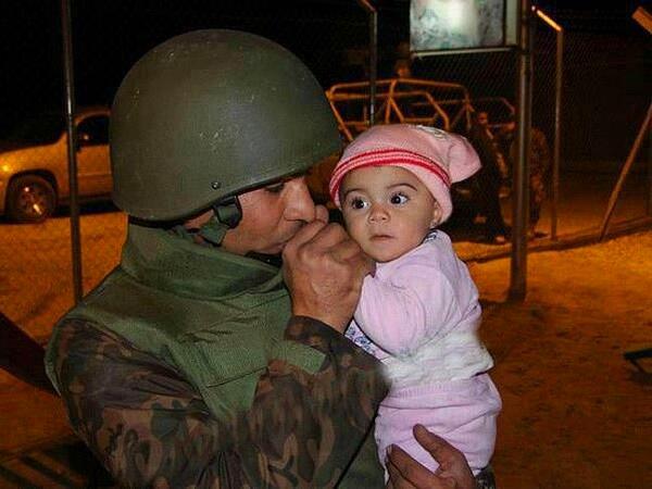 16. Ürdün askeri ülkesinden kaçan Suriyeli bebeğin ellerini ısıtmaya çalışıyor. (Suriye iç savaşı, 2013)