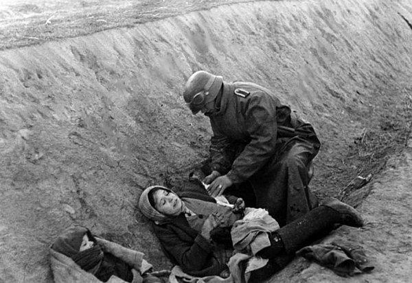 27. Bir Alman askeri yaralı Rus sivile ilk yardım uyguluyor. (II. Dünya Savaşı, 1941).