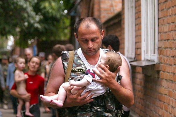 26. Bir Rus özel kuvvet polisi Beslan okul baskınından kurtarılan bebeği kucağında olay yerinden uzaklaştırıyor.