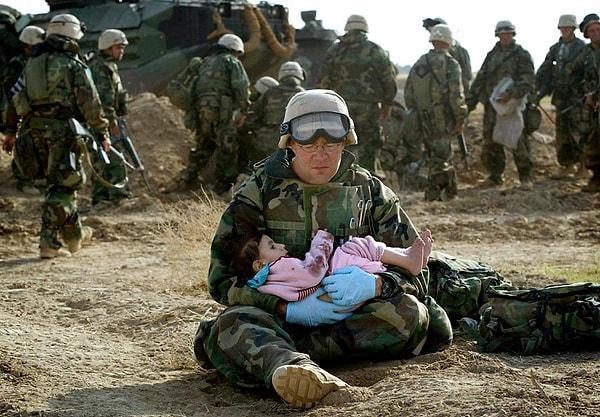 11. Yine Irak İşgali sırasında bir asker, az önceki çatışma sonrasında ailesini kaybeden küçük bir çocuğu yanına almış. (2003)