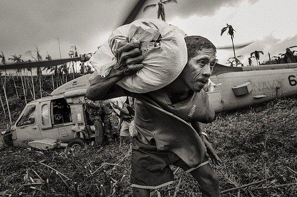 23. Haiyan tayfunu sonrası insanlara yardım için helikopterle yollanan paketlerin boşaltılmasına yardımcı olan yerel halk. 20 Kasım 2013