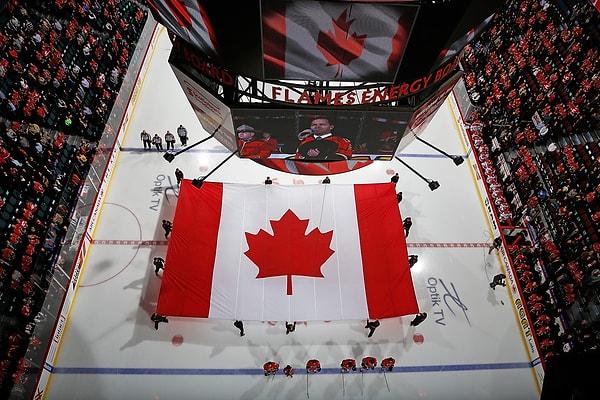 37. Scotiabank Saddledome'da yapılacak olan Calgary Flames ile Carolina Hurricanes arasındaki Buz Hokeyi maçı öncesi Ottawa silahlı saldırısı için yapılan saygı duruşunda açılan dev Kanada bayrağı. Calgary, Alberta, Kanada. 23 Ekim