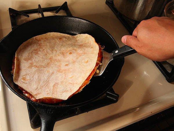 2. Peynir eriyip, üstteki hamur kıvrılmaya başladığında bir spatula yardımıyla pizzamızın hamurunu ters çeviriyoruz.