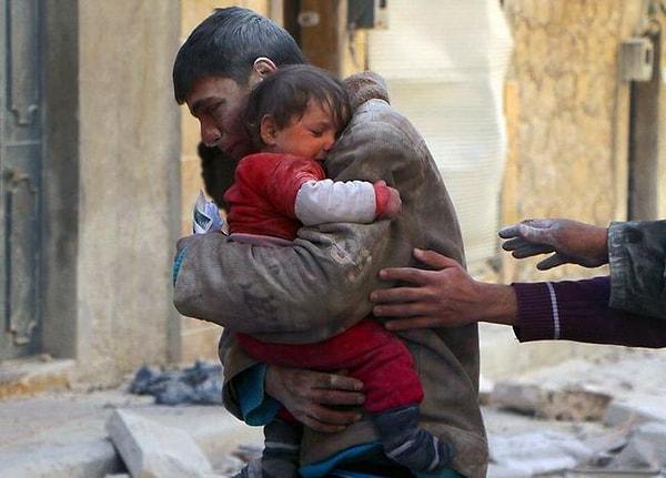 10. Bombalanan evden küçük kız kardeşini kurtaran ve ardından ona delice sarılan adam, Suriye.