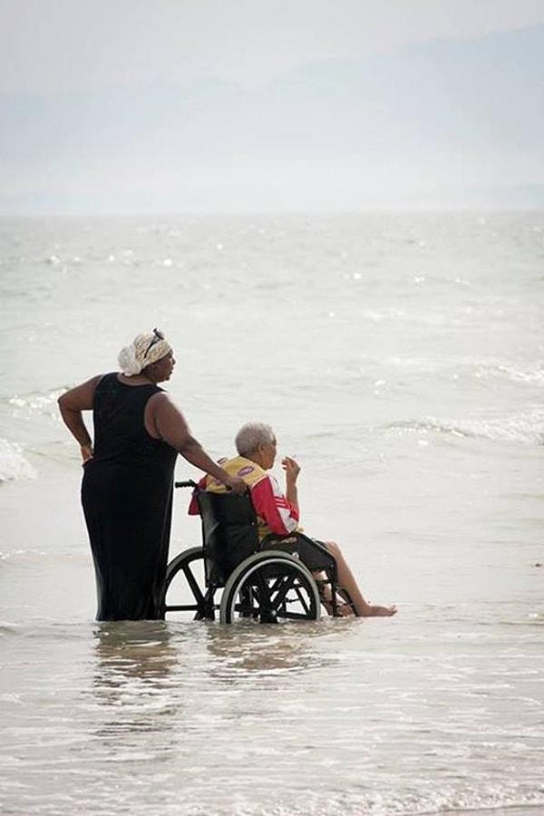 32. Annesine okyanus suları içerisinde yardım eden kadın, Güney Afrika.