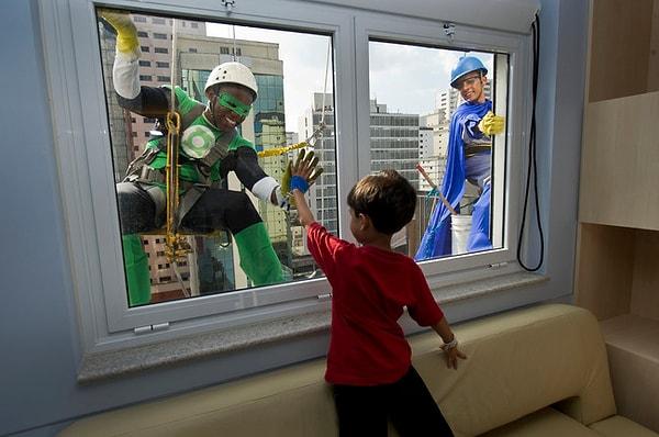 36. Çocuk hastanesinde yatan bir çocuk, camları silen görevlileri selamlıyor, Brezilya.
