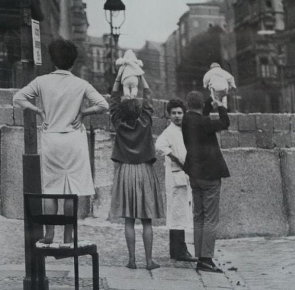 20. Batı Berlin'deki insanlar Doğu Berlin'deki büyük arkabalarına çocuklarını gösterirken, 1961