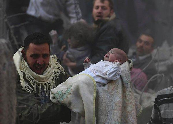 1. Beşşar Esad'e bağlı güçlerin hava saldırısından kurtulmayı başaran bir bebek güvenli bölgeye taşınıyor.