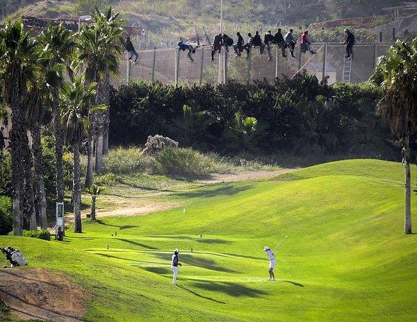 2. Göçmenler sınır telinden atlayarak İspanya'ya girmeye çalışırken bir kadın golf oynuyor.