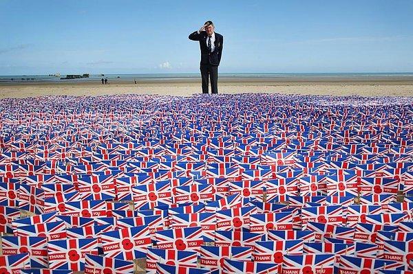13. İkinci Dünya Savaşı gazisi İngiliz Fred Holborn, Fransa sahillerine yerleştirilmiş bayrakları selamlıyor.