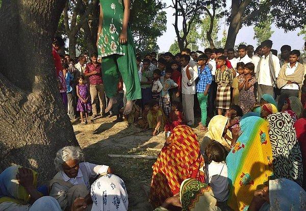 25. Tecavüz edilen ve öldürülerek bedenleri ağaca asılan 12 ve 14 yaşlarındaki iki kızın etrafında toplanan Hintliler.