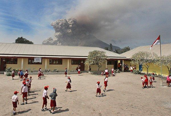 40. Endonezya'da bulunan Sinabung Dağı patlarken okul bahçesinde oyunlarına devam eden çocuklar.