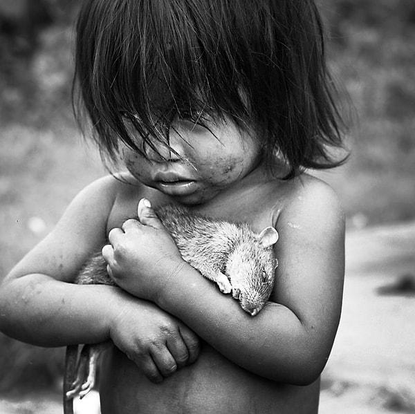 8. Küçük Guarani kız, ölü bir sıçanı elinde tutarken.