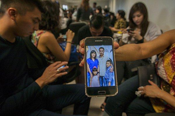 10. Endonezya, Surabaya'da bir kişi, kayıplara karışan Malezya uçağındaki yolcu akrabalarını gösteriyor.