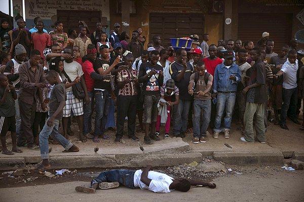 28. Sierra Leone'de, ebola şüphesiyle yerde yatan kişi ve etrafında sadece fotoğrafını çeken kalabalık.