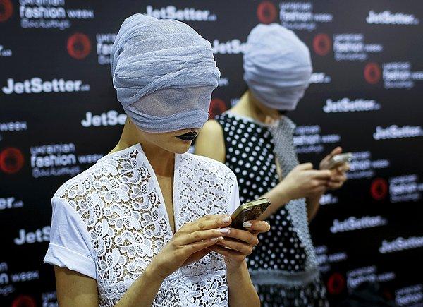 31. Ukrayna Moda Haftası'nda mankenler, sahneye çıkma bekleyişinde telefonlarıyla uğraşıyorlar.