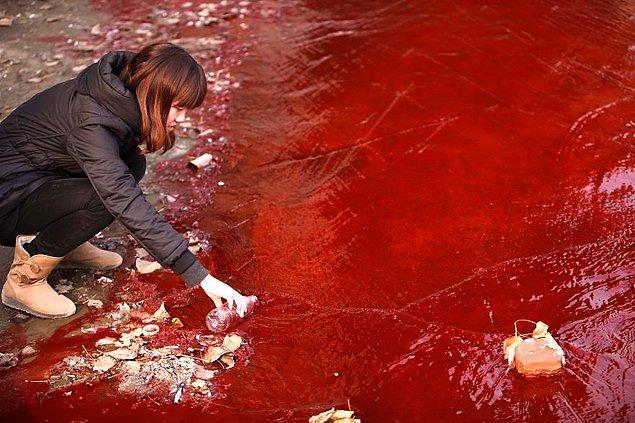 1. Gazeteci, rengi kırmızıya dönmüş Jianhe Nehri'nden örnek alıyor.