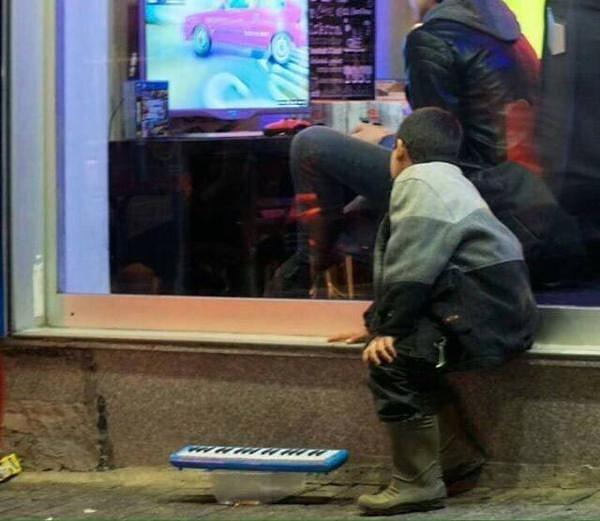 Bu fotoğraf objektiflere İstanbul'da yansıdı... Play Station Cafe'nin önünde, oyuncak orgunu çalarak para kazanmaya çalışan bir çocuk... Elbette gözü de, aklı da içeride