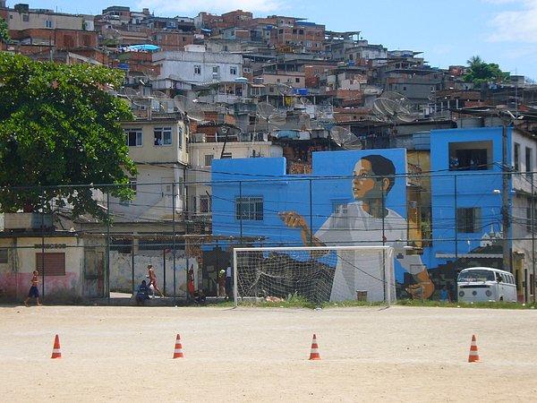 İlk önce bir futbol sahasının ardında duran 3 bitişik evin duvarlarına uçurtma uçuran bir çocuk resmediyorlar.