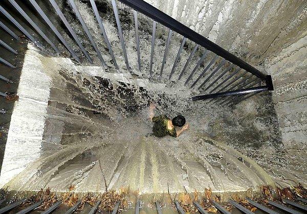 26. Yer altına inen merdivenlere akan su yüzünden aşağı inmekte zorlanan bir insan.