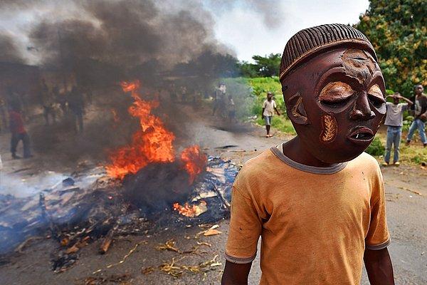 1. Bujumbura'da, Burundi cumhurbaşkanının üçüncü dönemine tepki gösteren protestocu, yanan bir barikatın hemen yanında maskesiyle dikkat çekiyor.