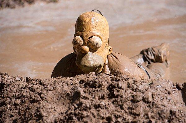 2. Almanya'daki kirli domuz festivaline katılan bir kişi, Homer Simpson maskesiyle çamurda yuvarlanıyor.