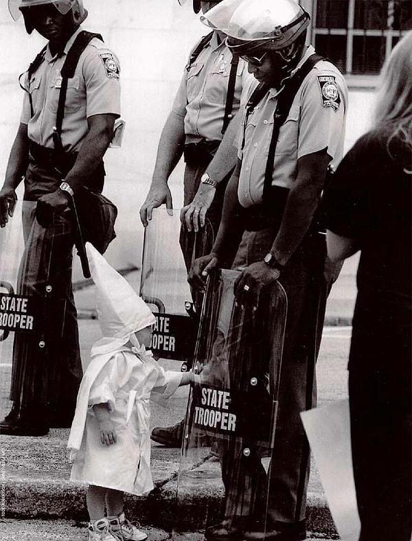 16. Irkçı Ku Klux Klan üyesinin çocuğu siyahi bir polisin kalkanında kendi yansımasına dokunurken: