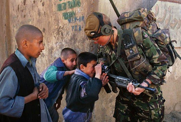 19. Bir askerin silahının dürbününden bakmaya çalışan Afgan çocuklar