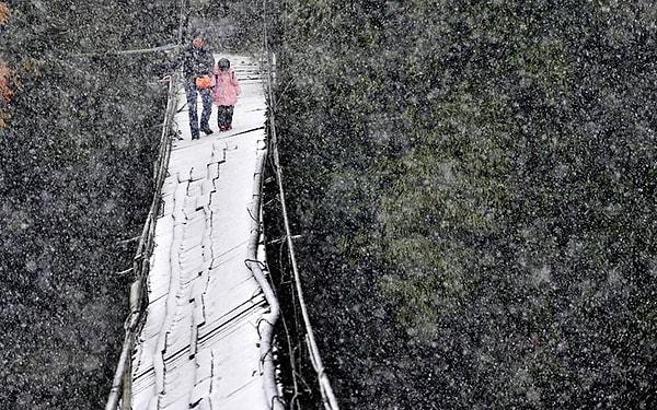 11. Karda zarar görmüş bir köprüden geçen öğrenci ve velisi. Dujiangyan, Sichuan Eyaleti, Çin.