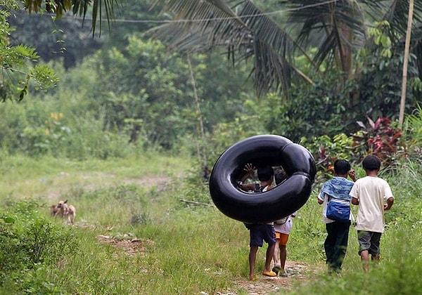 21. Lastikten bozma bir bot ile okulun yolunu tutan çocuklar. Rizal, Filipinler.