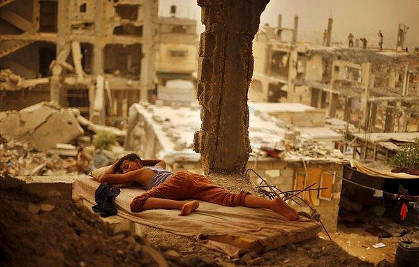 22. Filistinli bir çocuk, aliesinin evinin yıkıntıları arasında, bir yatağın üstünde uyurken. (8 Eylül)