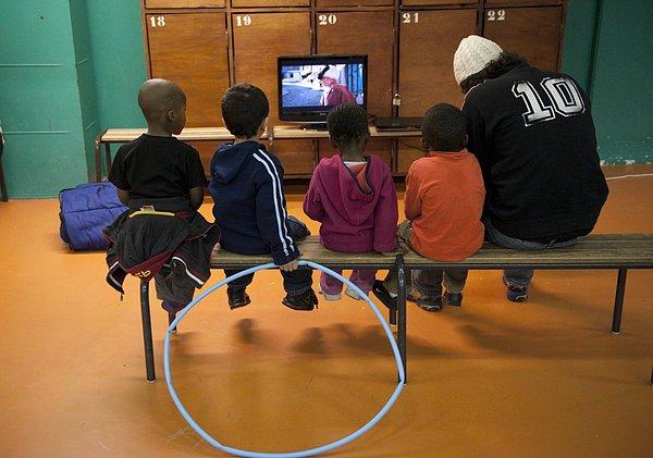 13. Paris'te bulunan Saint-Merri spor salonunda televizyon izleyen çocuklar.