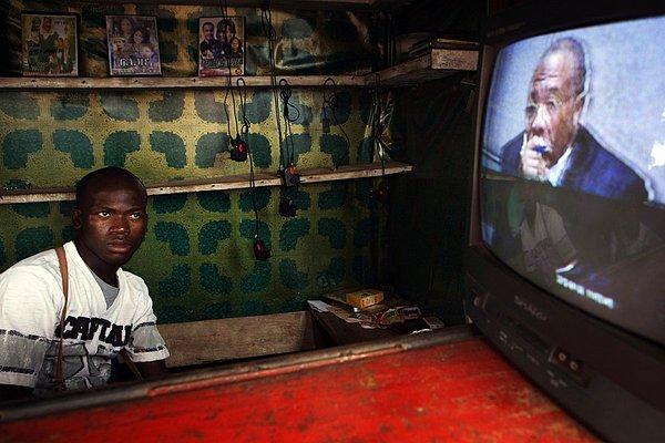 14. Liberyalı bir sokak satıcısı, zamanın Liberya Devlet Başkanı Charles Taylor'ın bir konuşmasını izlerken.