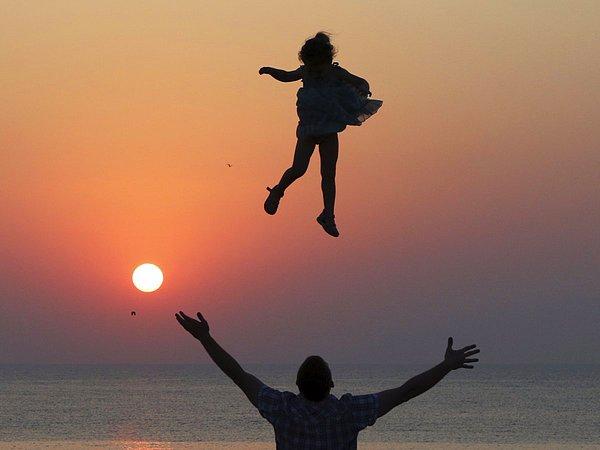 1. Kırım'ın Chersonesos Taurica bölgesindeki Karadeniz Limanı'nda bir adam, günbatımı sırasında küçük bir kızı havaya atarken, 25 Temmuz 2015.