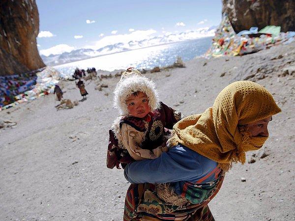 11. Çin'deki Tibet Özerk Bölgesi sınırları içinde yer alan ve kutsal olarak kabul edilen Namtso Gölü'nü sırtındaki çocuğuyla ziyaret eden bir kadın, 18 Kasım 2015.