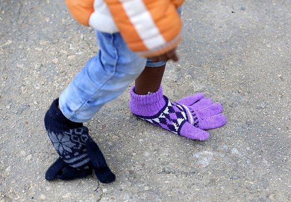 15. Sicilya'daki Pozzallo limanına gelen mültecilerden yalnızca biri; ayaklarına eldiven giyen küçük bir kız çocuğu. 16 Şubat 2015.