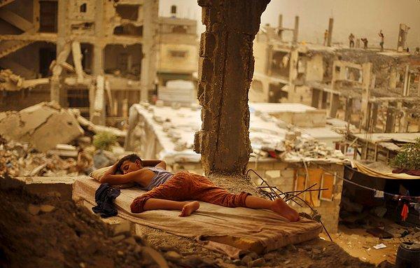 4. Gazze'deki kum fırtınası sırasında Filistinli bir çocuk, 2014 yılında İsrail toplarının enkaz haline getirdiği evinin içinde uyurken. 8 Eylül 2015.