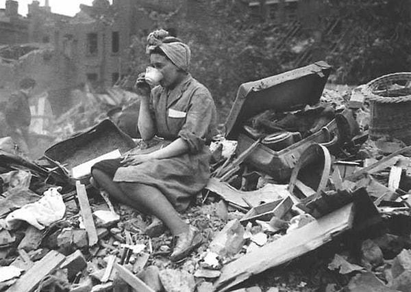 2. 1940'larda Almanya'nın Londra saldırısında bombalanmış binalar arasında askerlere karşı çay içen bir kadın.