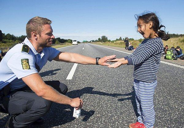 1. Danimarkalı bir polis, Padborg'un kuzeyindeki E45 otobanında göçmen bir kız çocuğu ile tahmin oyunu oynuyor. 9 Eylül 2015.