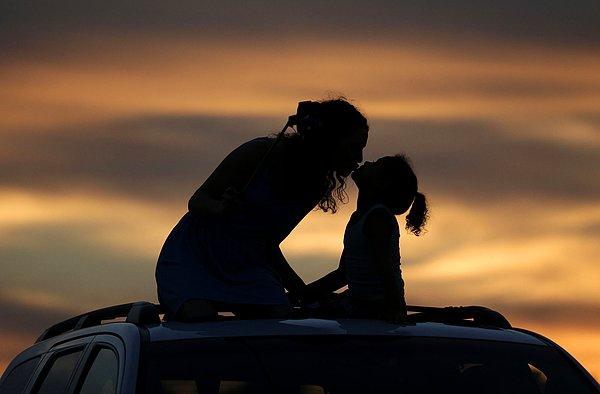 27. Savannah Anderson, bir ayçiçeği tarlasını görmek için arabalarının üzerine çıktıkları sırada kız kardeşi Macy Saunders'ı (6) öpüyor. 5 Eylül 2015.